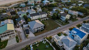 An aerial view of a coastal residential area with houses, a beach, and a road. - Roof Top Deck w/ Ocean Views, Heated Pool Access (Tybee Island)