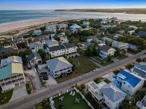 An aerial view of a coastal residential area with houses, a beach, and a road. - Roof Top Deck w/ Ocean Views, Heated Pool Access (Tybee Island)
