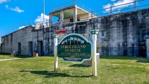 A sign for Tybee Island Museum with a historical building in the background. - Roof Top Deck w/ Ocean Views, Heated Pool Access (Tybee Island)