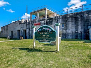 A sign for Tybee Island Museum with a historical building in the background. - Roof Top Deck w/ Ocean Views, Heated Pool Access (Tybee Island)