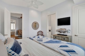 A bedroom with a bed, a television, a fish decoration, and a mirror on the wall.