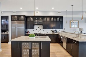 A modern kitchen with dark cabinetry, a central island with a sink, and stainless steel appliances.