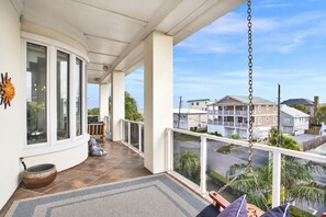 A balcony with a view of a residential area, a chair, a small table, and a decorative pot.