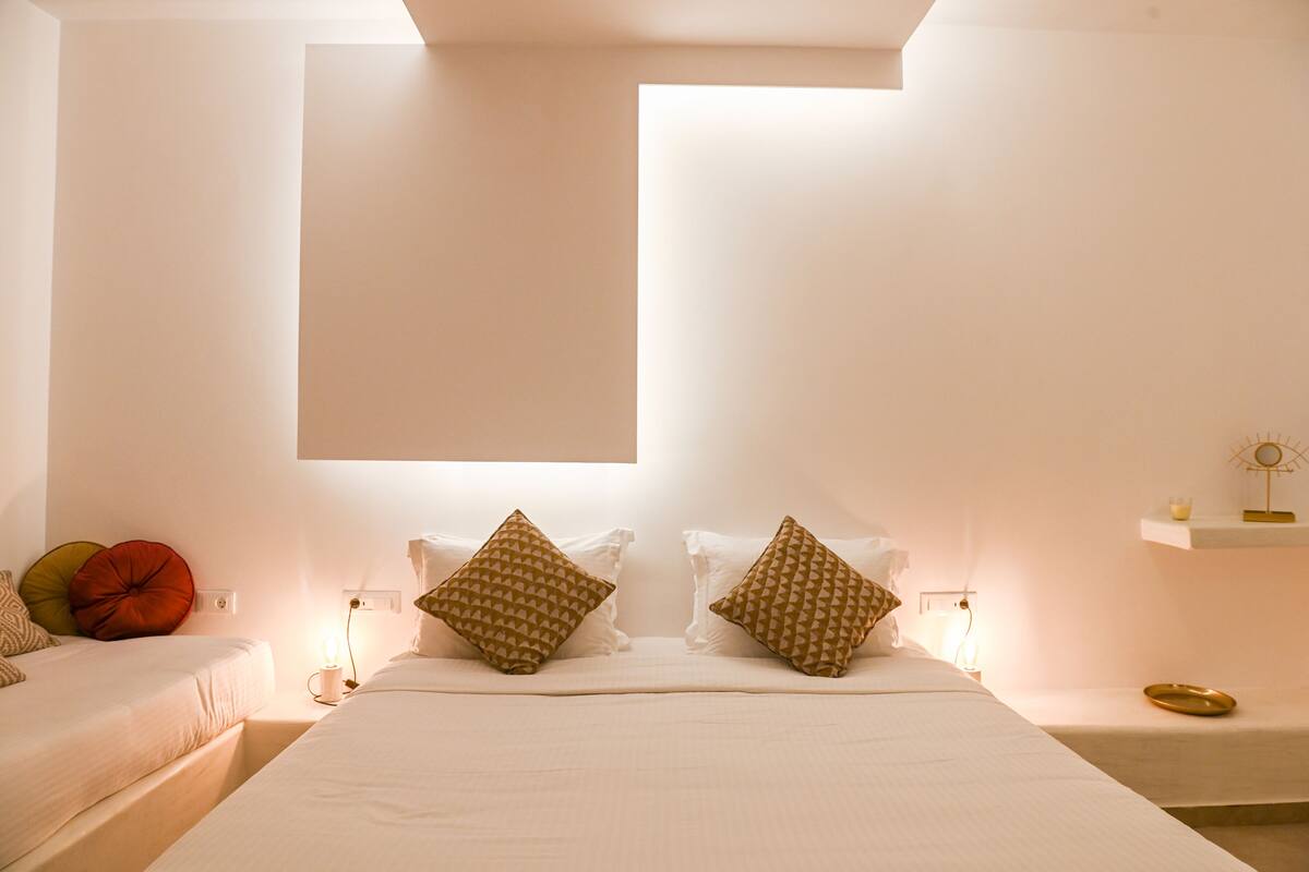 A hotel room with two beds, a large window, and a bedside table with a lamp.