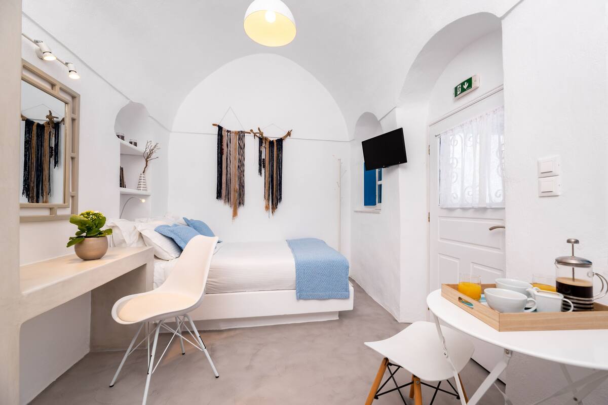 A modern hotel room with a bed, a desk, a chair, a TV, and a breakfast tray.