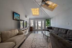 Relax in this stylish living room with a large window offering a view of the outdoors, a flat-screen TV, and a comfortable sofa.