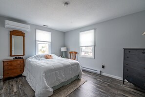 Relax in this serene bedroom with a large bed, dresser, and mirror.