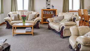 A spacious living room with two leather sofas, a wooden coffee table, and a bookshelf.