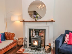 A cozy living room with a fireplace, a round mirror above it, and two sofas with cushions. - 8 Pedwell Way (Berwick-upon-Tweed)