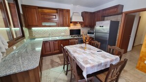 Eine Küche mit Holzschränken, Granit-Arbeitsplatten, einem Esstisch mit Stühlen und einem Kühlschrank.
