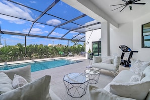 Un espace piscine extérieur moderne doté d’un toit en verre, de mobilier blanc et d’équipements de musculation.