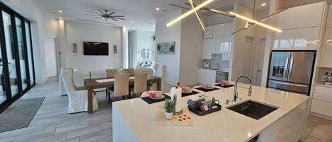 A modern kitchen with a central island, built-in appliances, and a dining area with a large window.