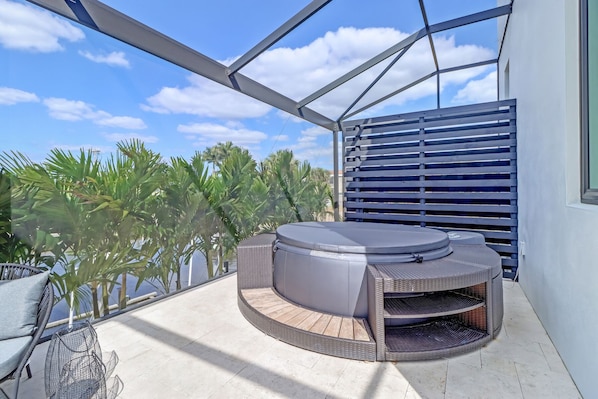 Relax in a serene outdoor oasis with a hot tub and wicker seating area.