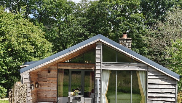 A log cabin with a glass patio, a dining area, and a large window. - The Hare's Shack (Kendal)