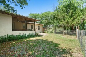 A single-story house with a covered patio, a fenced yard, and a large tree. - Cedar Hideaway! (Crystal River)