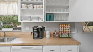 A kitchen with white cabinets, a coffee maker, and a dish rack. - Cedar Hideaway! (Crystal River)