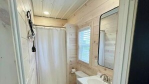 Une petite salle de bain comprenant des toilettes, un lavabo et un espace douche.