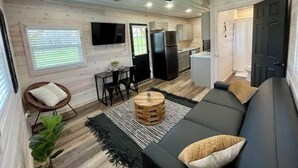 Un espace de vie compact comprenant un canapé, un coin repas, une cuisine et un ventilateur de plafond.