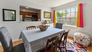 A dining area with a table set for four, wooden chairs, a woven basket, and a colorful rug. - Cheerful 3-bedroom private home minutes to beach (Bay St. Louis)