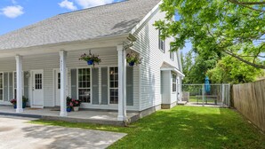 A white house with a covered porch, a fenced yard, and a wooden fence. - Cheerful 3-bedroom private home minutes to beach (Bay St. Louis)