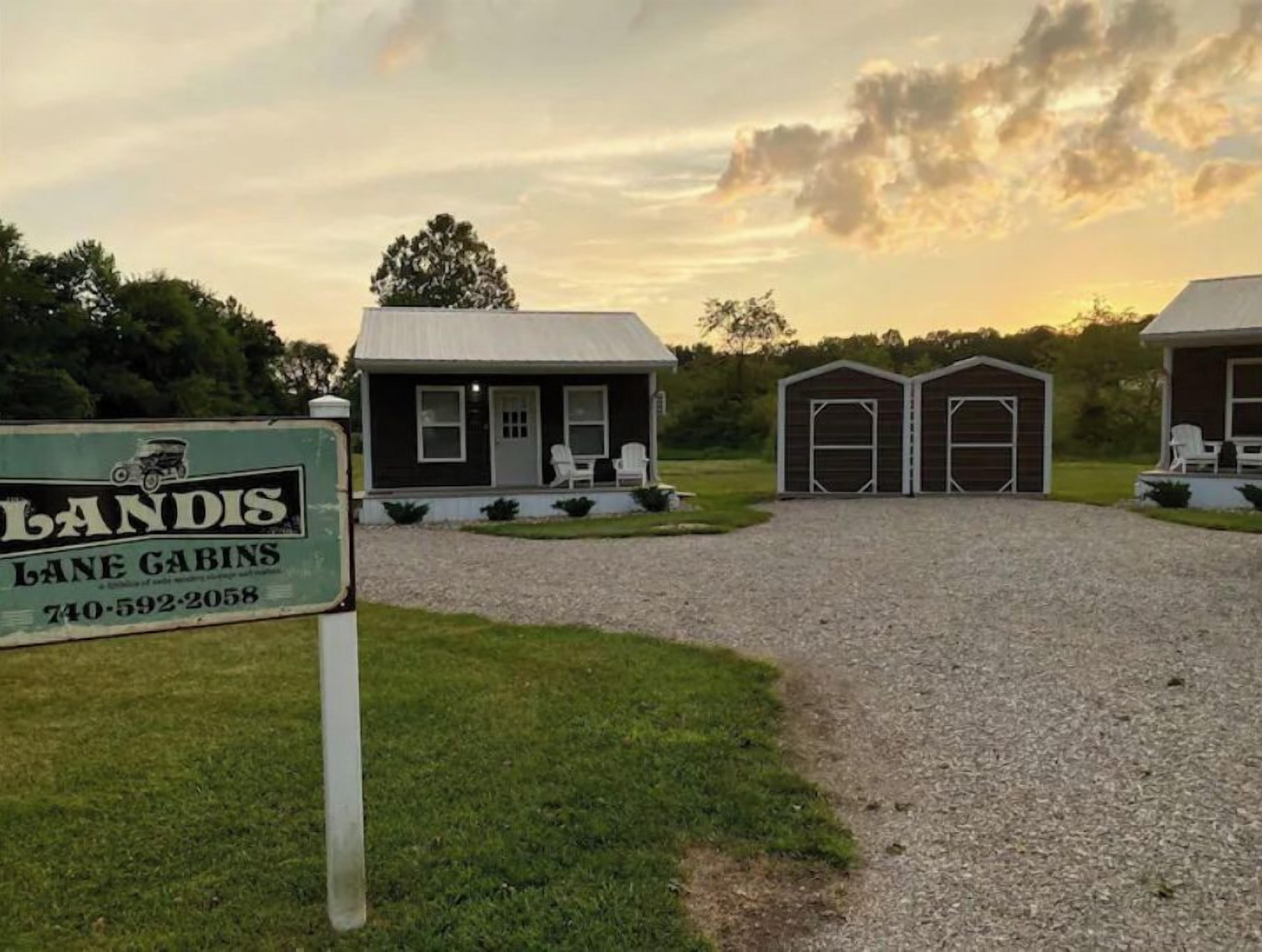 A property with a gravel driveway leading to a small house with a porch and two attached garages.