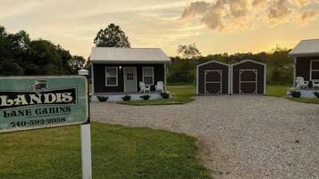 A property with a gravel driveway leading to a small house with a porch and two attached garages.