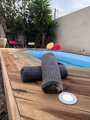 A wooden poolside lounge with a pool, lounge chairs, and a towel. - Charming, air-conditioned house with a swimming pool in a quiet neighborhood of Carcassonne (Carcassonne)