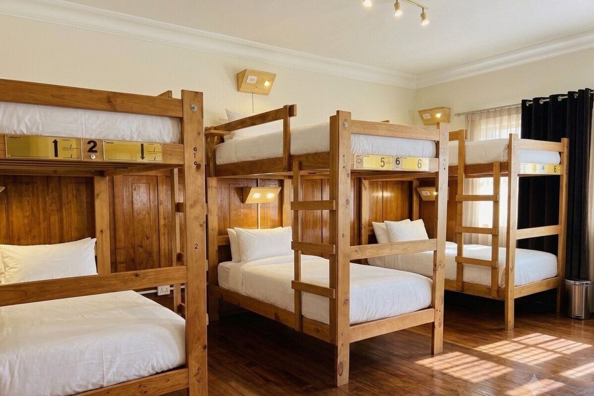 A room with bunk beds, wooden walls, and a window with curtains.