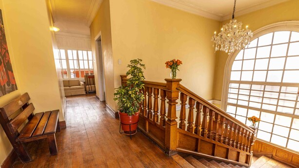 A wooden staircase with a chandelier, a bench, and a potted plant. - Eco Inn (Cusco)