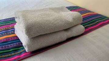 Una cama con un almohadón blanco y una manta a rayas de colores.