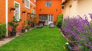 A courtyard with a green lawn, outdoor seating, and potted plants. - Eco Inn (Cusco)