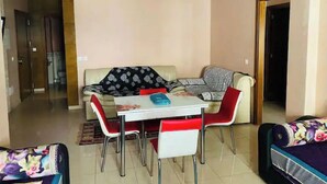 Ein Wohnzimmer mit einer Couch, einem Esstisch mit Stühlen und einem gemusterten Teppich.