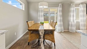 Un comedor con una mesa de madera, sillas de mimbre y cortinas a rayas.
