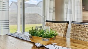 Una mesa de madera con una cesta trenzada que contiene plantas verdes y frascos de vidrio.