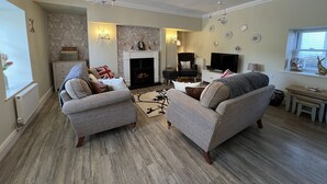 A living room with two grey sofas, a fireplace, a TV, and a chandelier. - May Bell Cottage (King's Lynn)