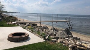 A waterfront deck with a fire pit, a metal railing, and a view of the water.