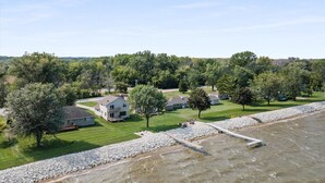 A residential area with houses, a paved walkway, and a rocky shoreline.