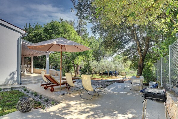 An outdoor patio with a pergola, lounge chairs, and a grill. - Cottage only 20 meters from the beach (Premantura)