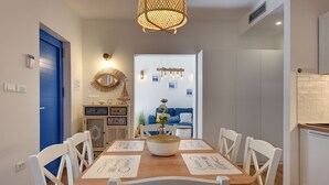 A dining area with a wooden table, white chairs, and a central decorative bowl. - Cottage only 20 meters from the beach (Premantura)