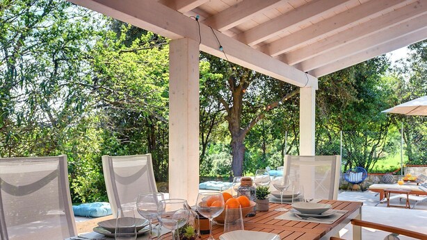 An outdoor dining area with wooden tables and chairs, surrounded by lush greenery. - Cottage only 20 meters from the beach (Premantura)