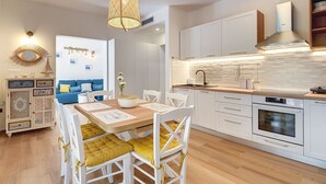A modern kitchen with white cabinetry, a wooden countertop, and a built-in oven. - Cottage only 20 meters from the beach (Premantura)