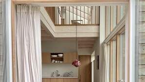 Una cocina compacta con armarios de madera, una mesa de comedor con sillas y una lámpara colgante roja.