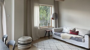 Una sala de estar acogedora con un sofá blanco, un reposapiés a rayas y una lámpara colgante.