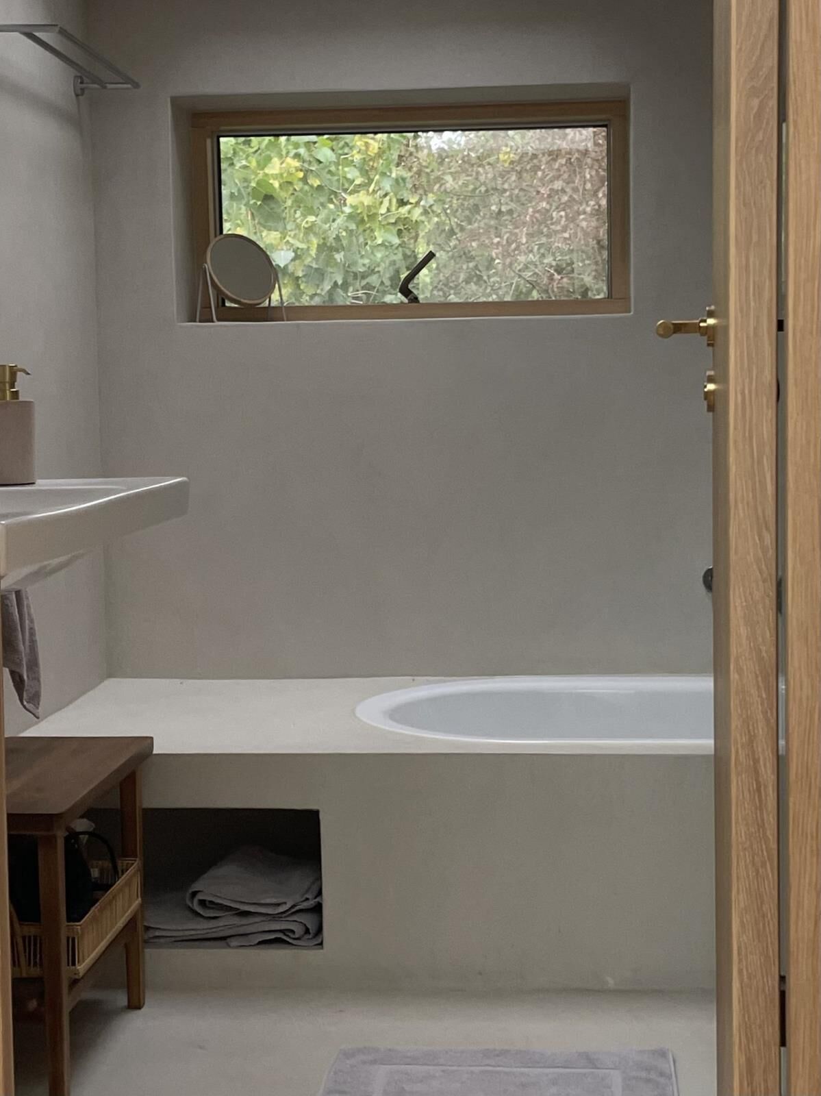 Un baño con ventana, lavamanos, espejo y bañera.