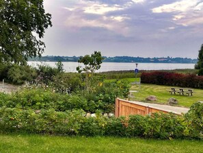A lakeside garden with a picnic table, a wooden shed, and a lamppost.
