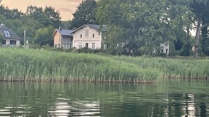 Ett hus vid en sjö med ett stort träd i förgrunden.