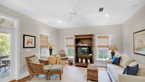 A spacious living room with a large window, a ceiling fan, a wooden bookshelf, and a comfortable seating area. - 🐟350yds 2 Beach-Porch-Magnolia Cottage (Inlet Beach)