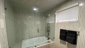 Une salle de bain moderne dotée d’une douche à parois de verre, d’une baignoire et d’un porte-serviettes.