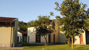 Un edificio con techo de tejas, césped y árboles.