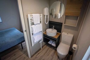 Ein kleines Hotelbad mit Waschbecken, Toilette, Handtuchhalter und Spiegel.